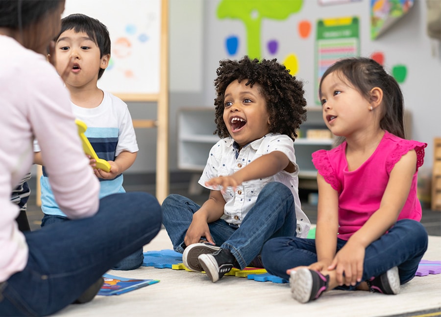 Image of three children and a caregiver engaged in circle time